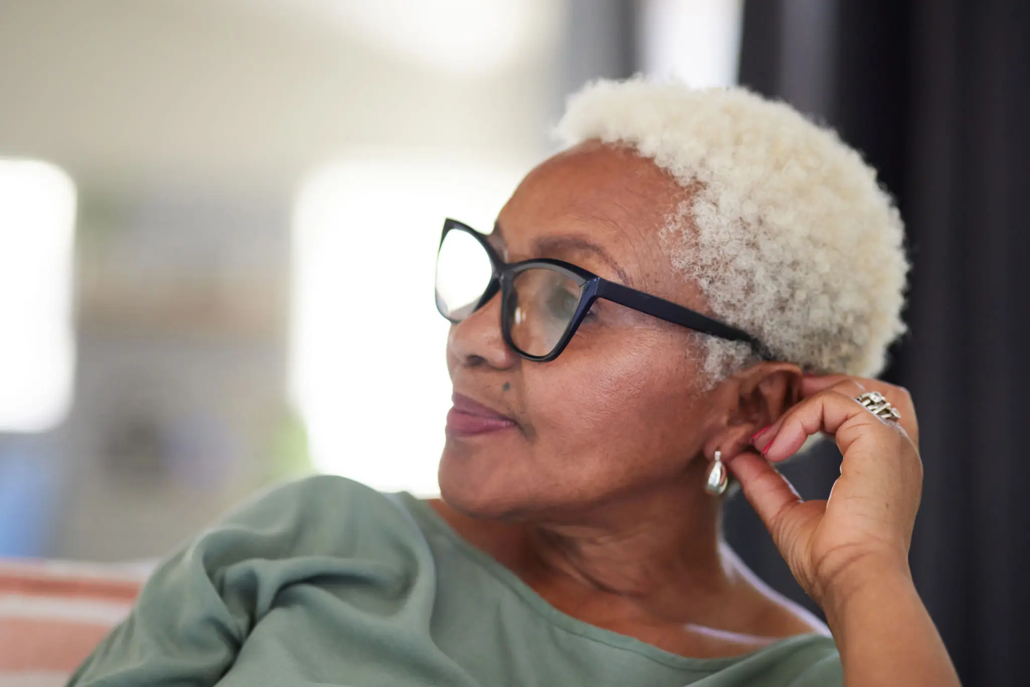 Thoughtful woman with glasses gazing sideways.
